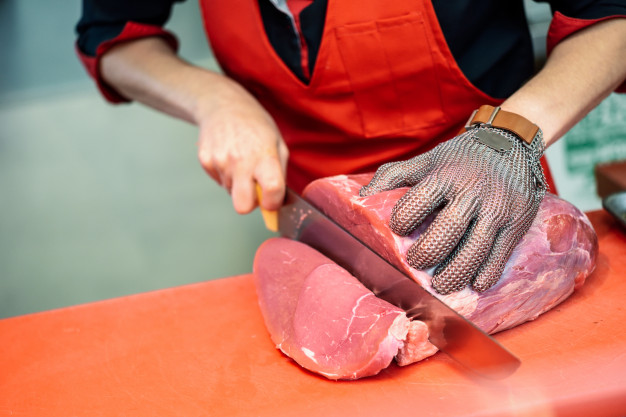 woman-cutting-fresh-meat-butcher-shop-with-metal-safety-mesh-glove_1139-1726